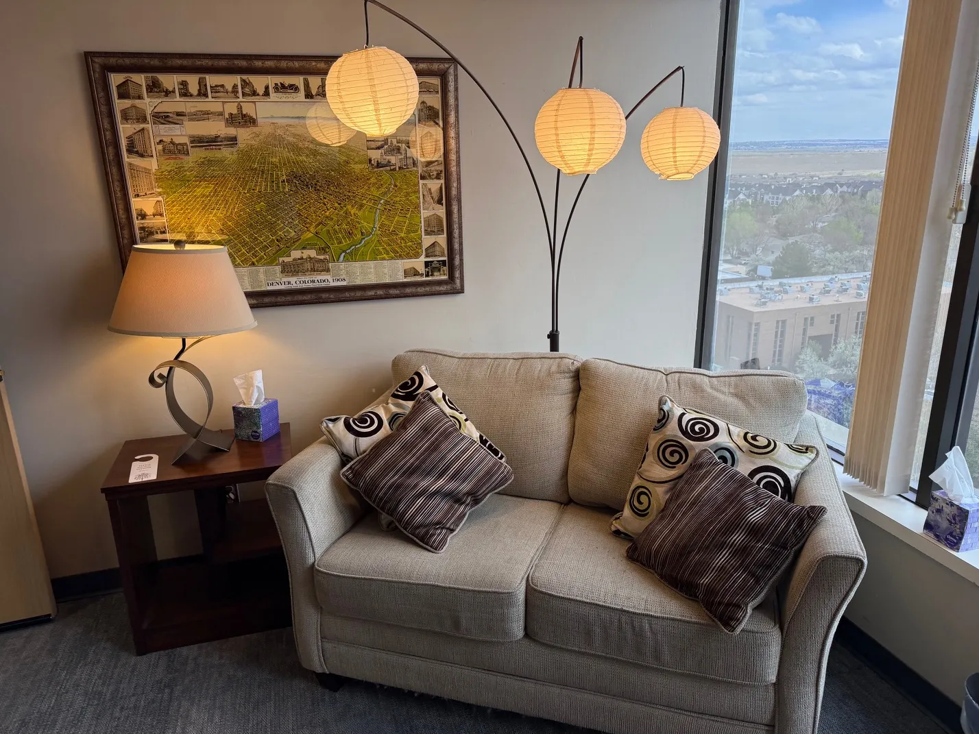 Therapy room with a loveseat, paper lanterns, and a framed 1908 map of Denver on the wall.