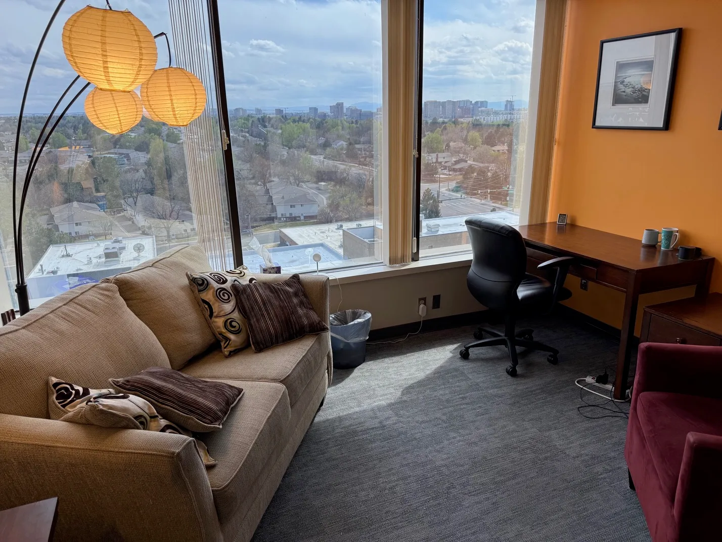 Therapy room with a long couch, desk, and a window looking out toward the foothills.